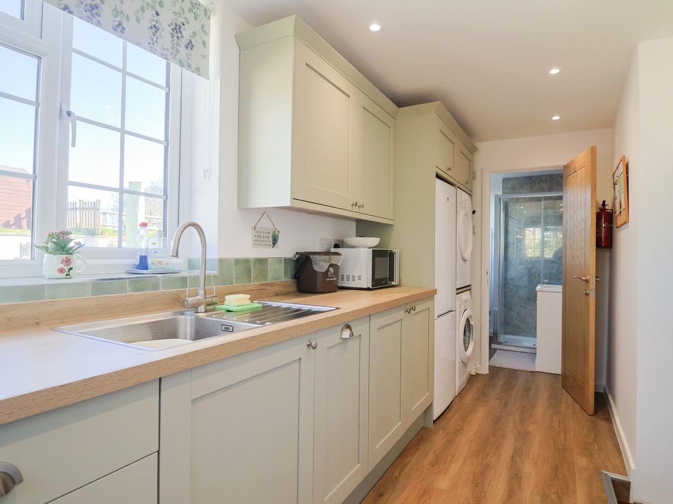 A kitchen with appliances and a door to another room at The Old Smithy Dottery near Bridport