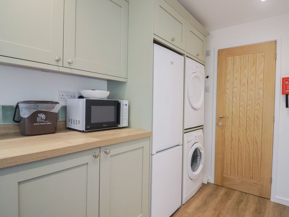 A utility room with appliances and cabinets at The Old Smithy Dottery near Bridport