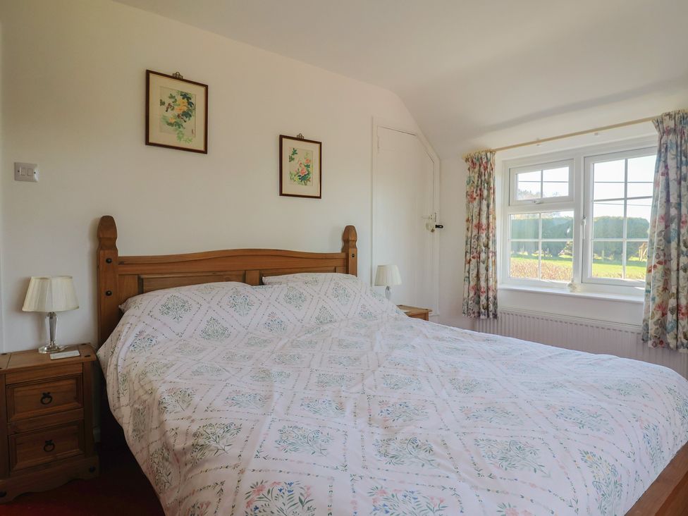 A bedroom featuring a bed with nightstands and a window at The Old Smithy in Dottery near Bridport