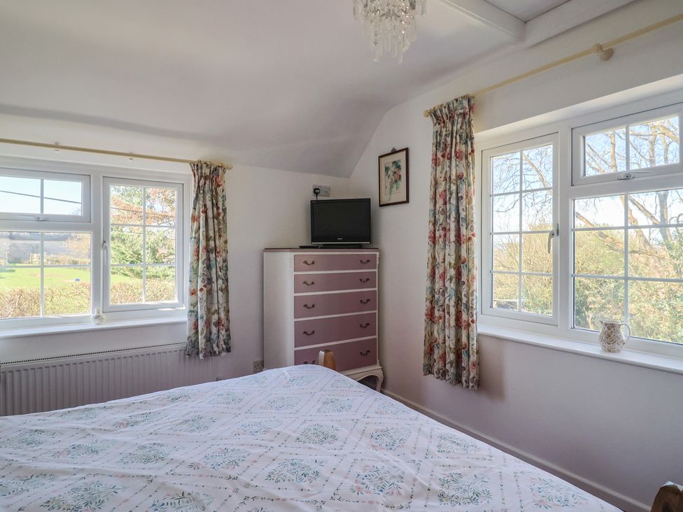 A bedroom with a bed, dresser, and television at The Old Smithy in Dottery near Bridport