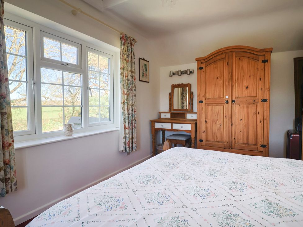 A bedroom with a bed, wardrobe and dressing table at The Old Smithy in Dottery near Bridport