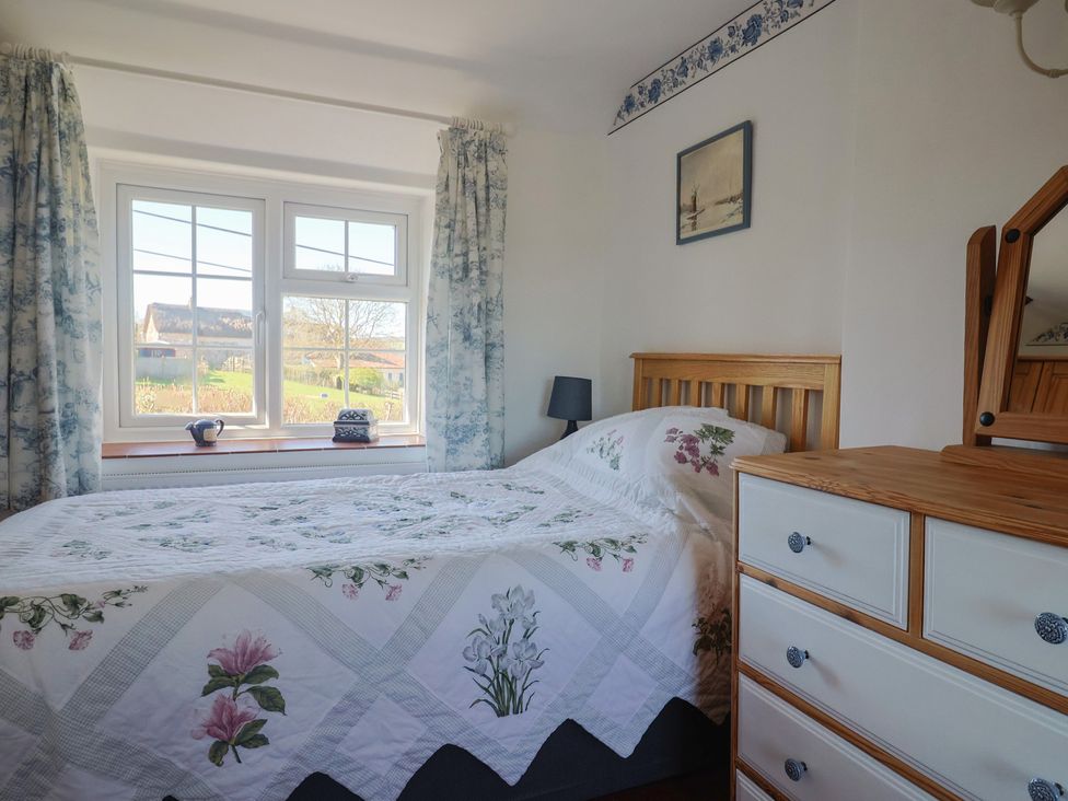 A bedroom with a bed and window at The Old Smithy Dottery near Bridport