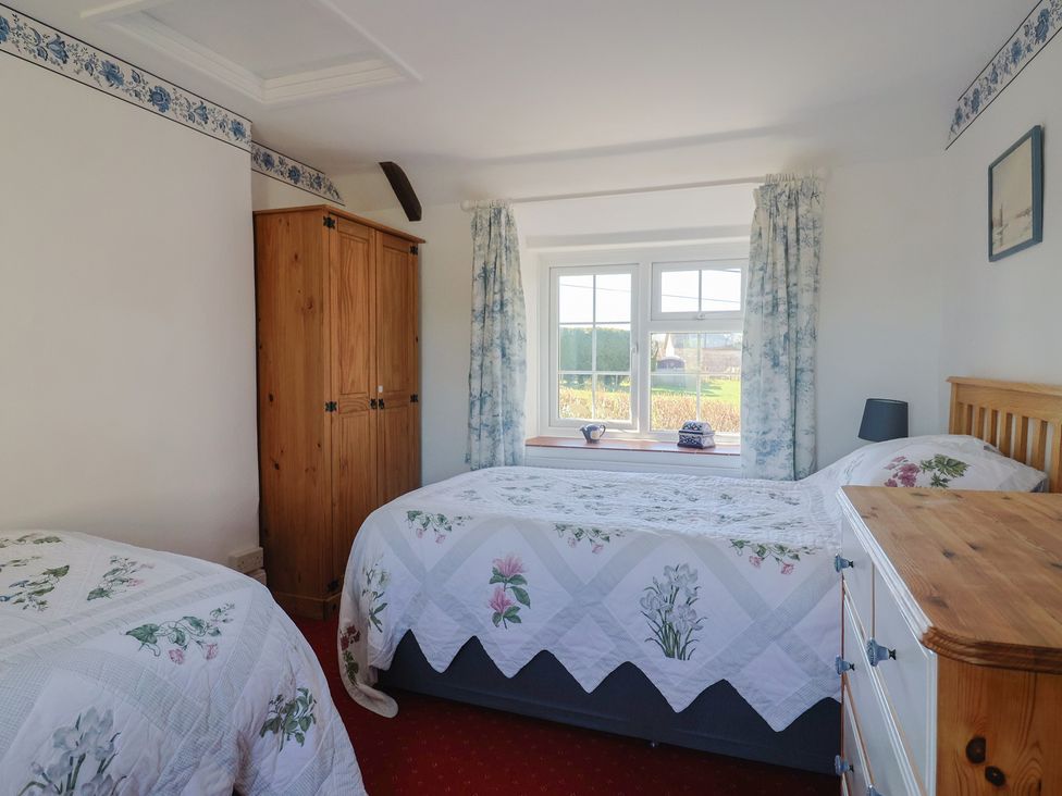 A bedroom with a bed, wardrobe, and window at The Old Smithy in Dottery near Bridport