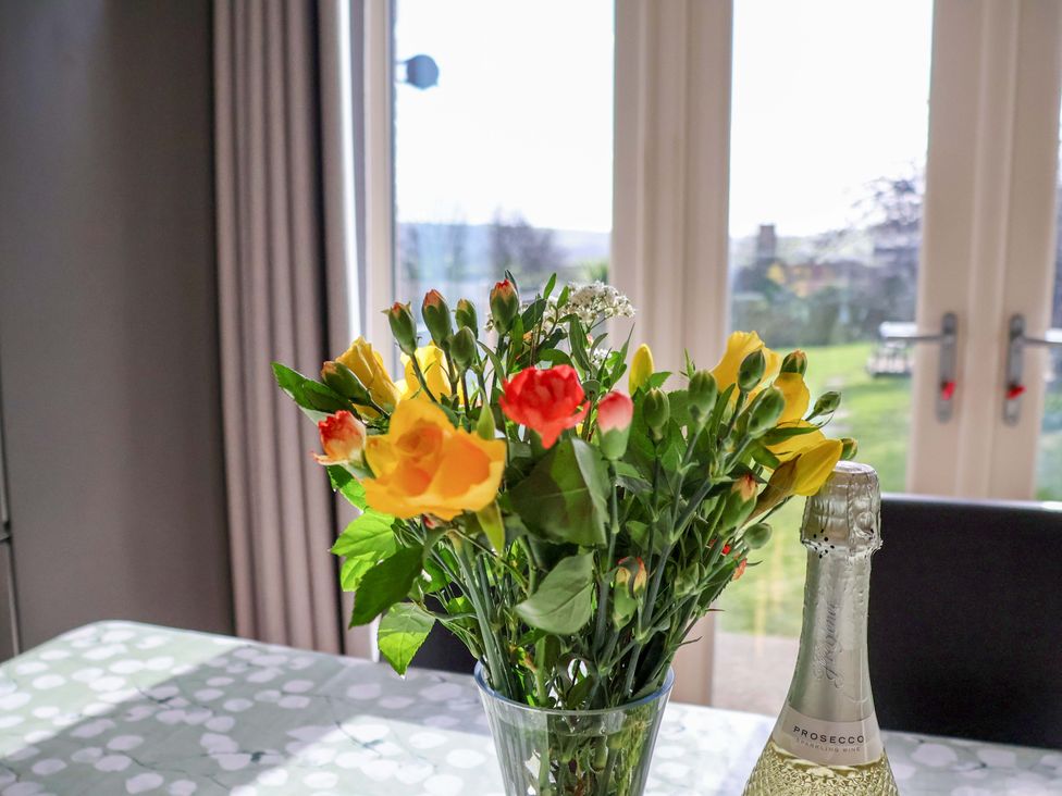 A dining room table with a flower vase and prosecco at Heather Croft in Robin Hood's Bay