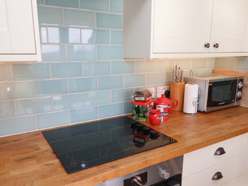A kitchen counter with stove and microwave at Heather Croft in Robin Hood's Bay