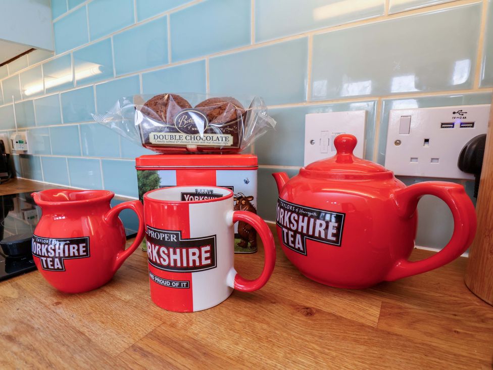 A kitchen with a teapot, mug, milk jug, biscuits, and tea box at Heather Croft in Robin Hood's Bay