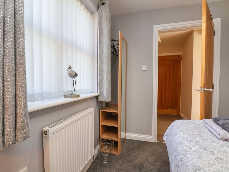 A bedroom with a window, wardrobe, and wooden door at Heather Croft in Robin Hood's Bay