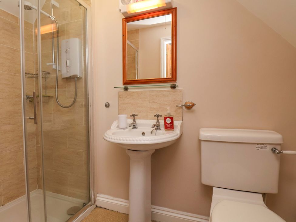 A bathroom with shower, sink, toilet, and mirror at Heather Croft in Robin Hood's Bay