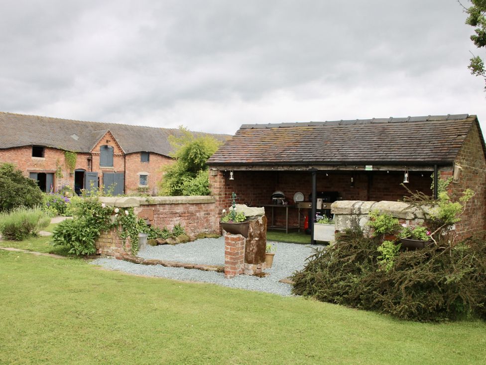 An outdoor area with brick buildings and a shelter at Lake View Cottage Audley Brow near Market Drayton
