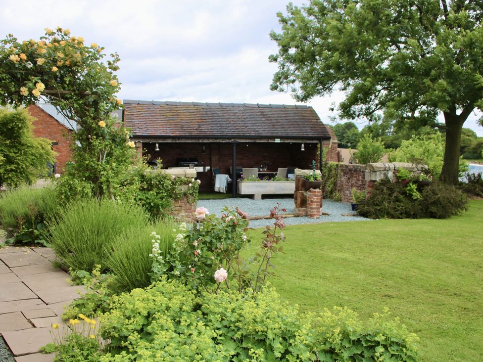 A garden with seating area and flower beds at Lake View Cottage in Audley Brow near Market Drayton