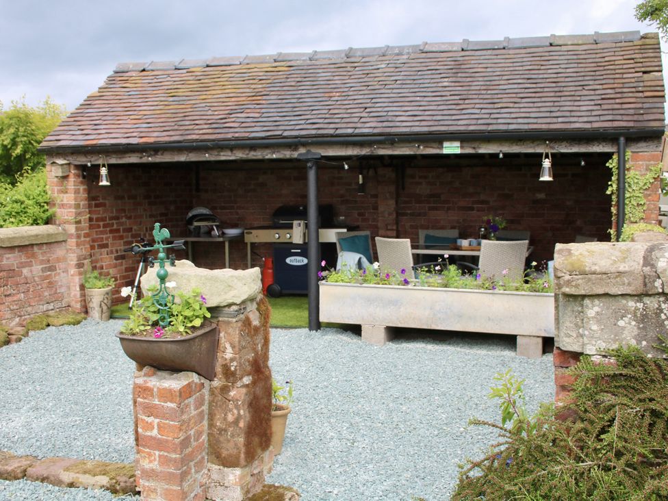An outdoor kitchen with a table and chairs at Lake View Cottage Audley Brow near Market Drayton
