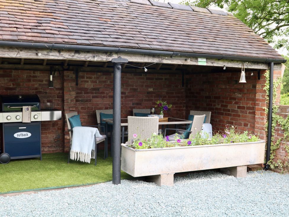 An outdoor seating area with a grill and table at Lake View Cottage in Audley Brow near Market Drayton