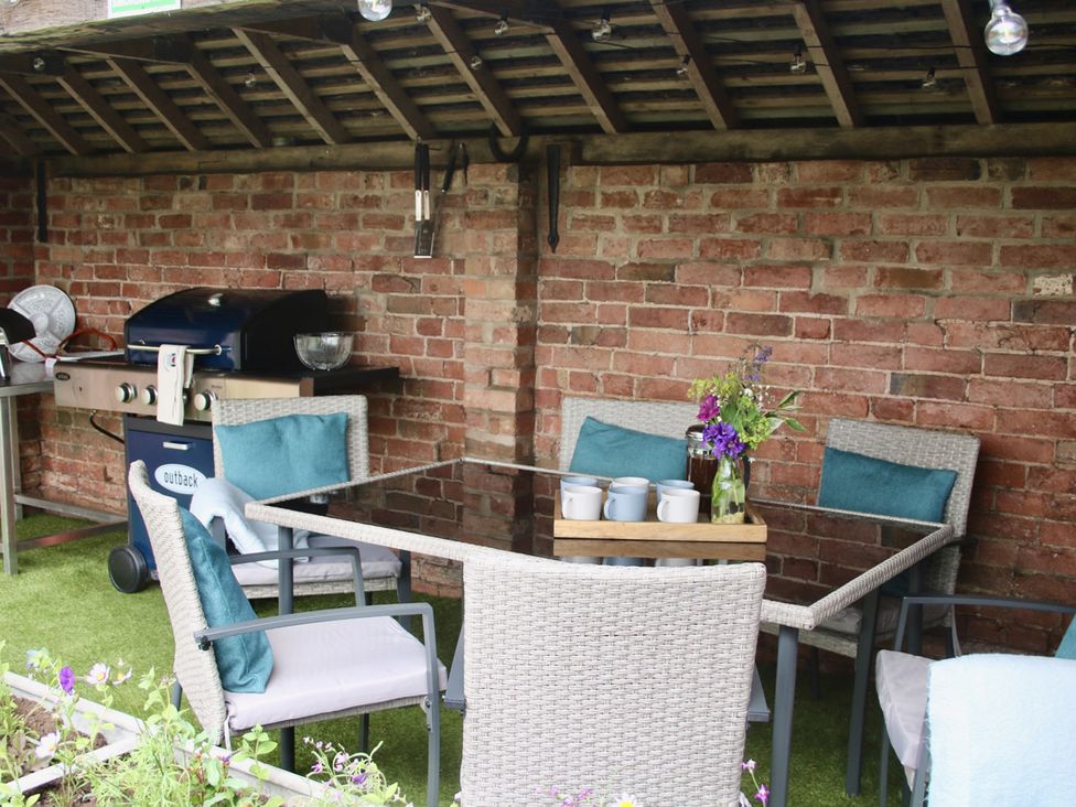An outdoor dining area with a grill, table, and chairs at Lake View Cottage in Audley Brow near Market Drayton