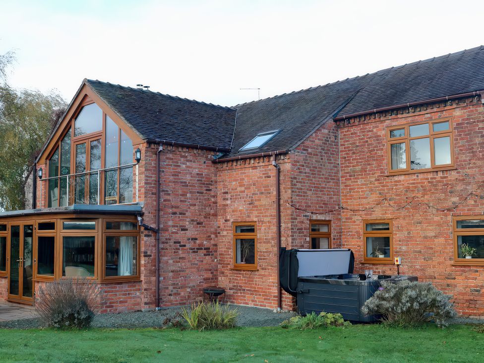 A brick house with a hot tub and garden at Lake View Cottage in Audley Brow near Market Drayton