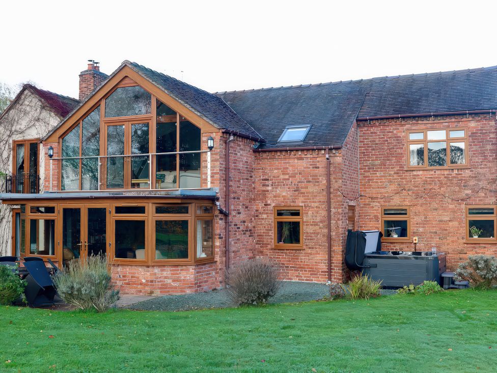 An outdoor view of a house with a garden and hot tub at Lake View Cottage Audley Brow near Market Drayton