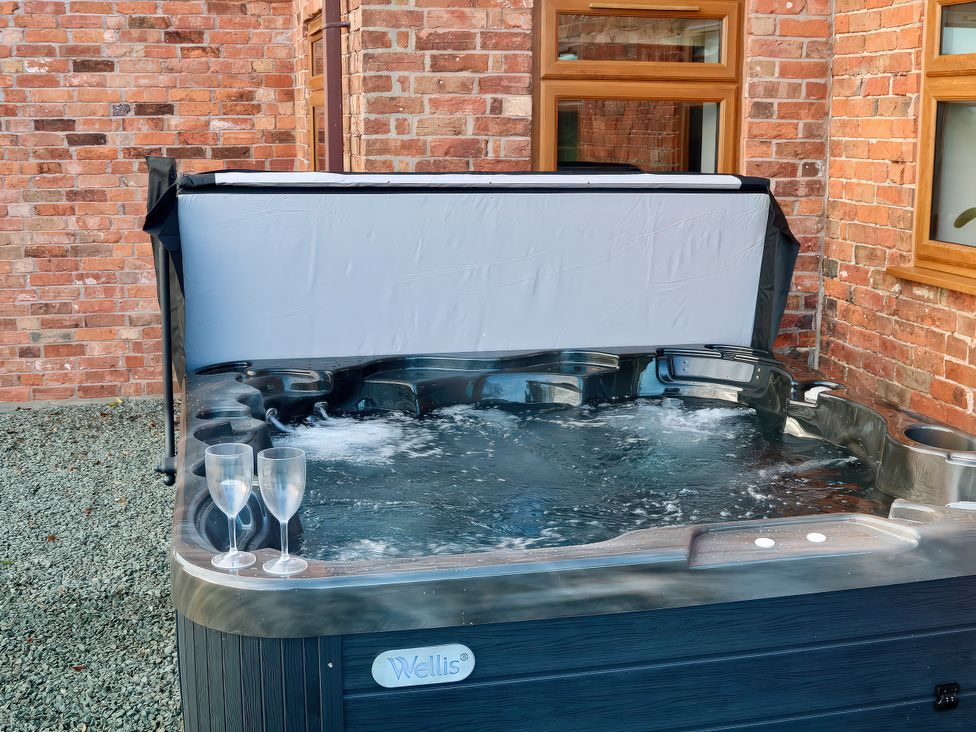 A hot tub with water and glasses beside it at Lake View Cottage Audley Brow near Market Drayton