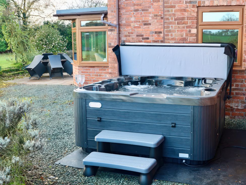A hot tub with steps and a table with chairs at Lake View Cottage Audley Brow near Market Drayton