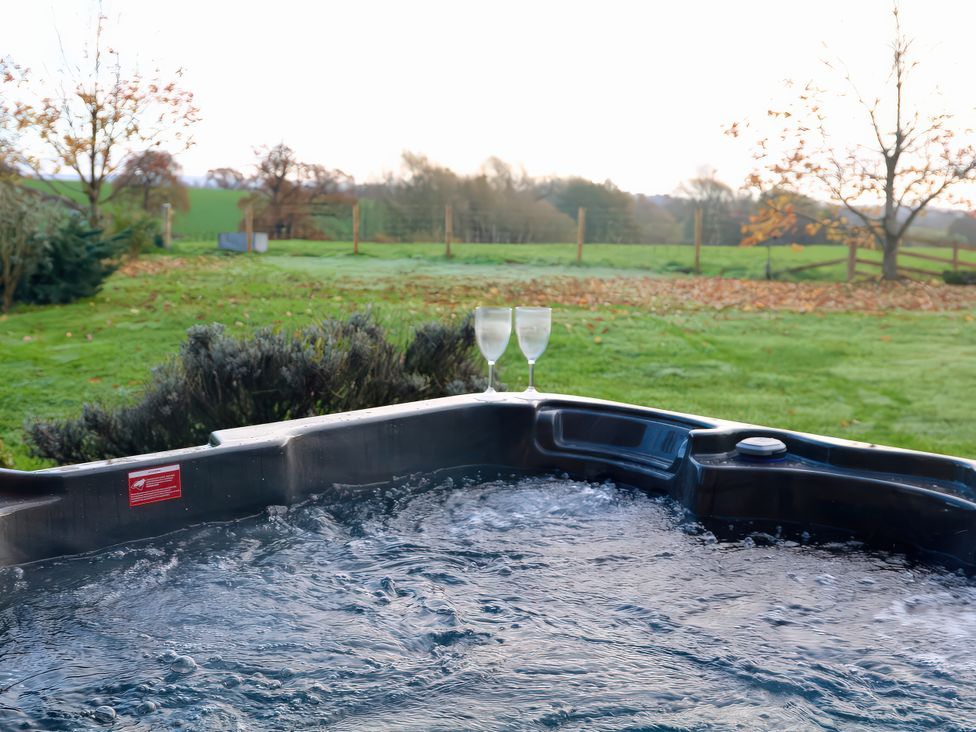 A hot tub with water and glasses beside it at Lake View Cottage Audley Brow near Market Drayton