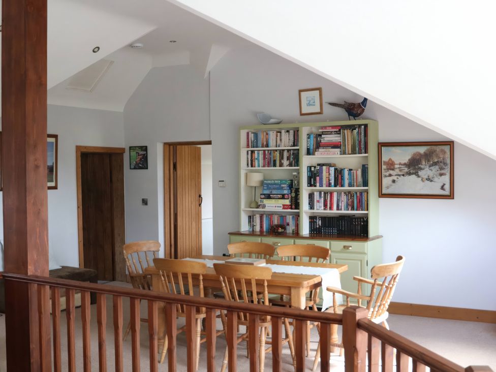 A dining room with a table and bookshelf at Lake View Cottage Audley Brow near Market Drayton
