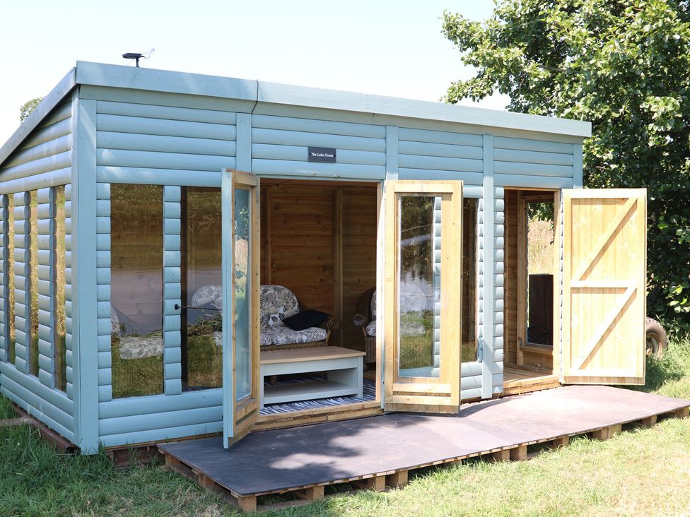 A wooden cabin with glass windows and doors at Lake View Cottage near Audley Brow