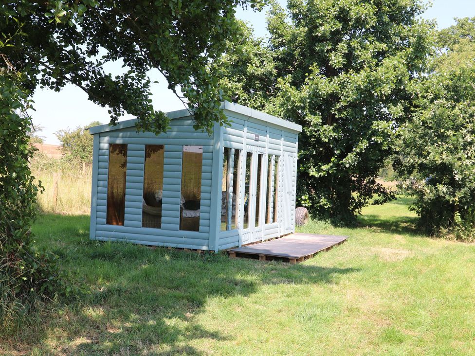 A wooden shed with multiple windows on a deck in Lake View Cottage Audley Brow near Market Drayton