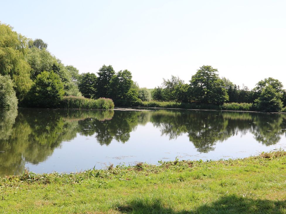 A lake with trees reflecting on the water at Lake View Cottage Audley Brow near Market Drayton