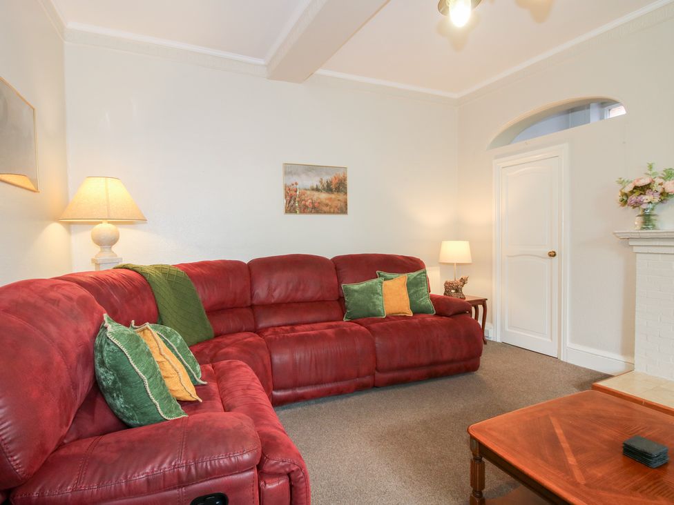 A living room with a red sofa and a lamp at The Laurels in Bishop's Castle