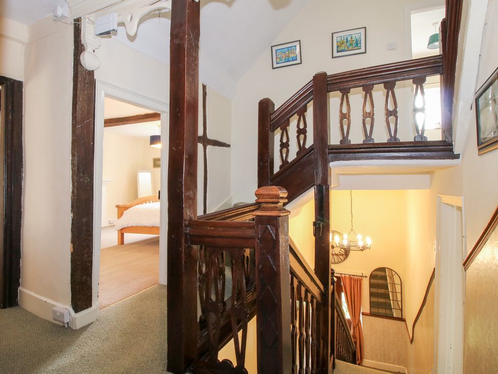 A staircase with wooden railing and light fixture at The Laurels in Bishop's Castle