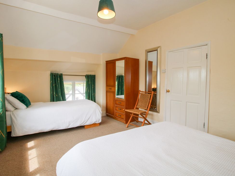 A bedroom with two beds and a wardrobe at The Laurels in Bishop's Castle