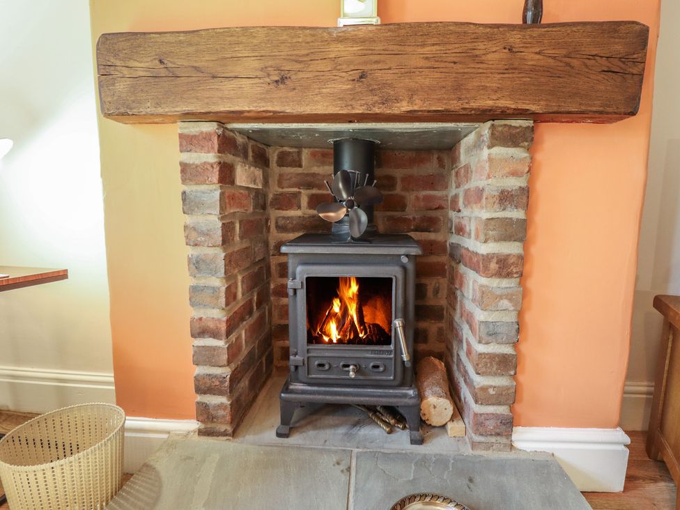 A fireplace with a wood stove and brick surround at 29 High Street in Aldeburgh