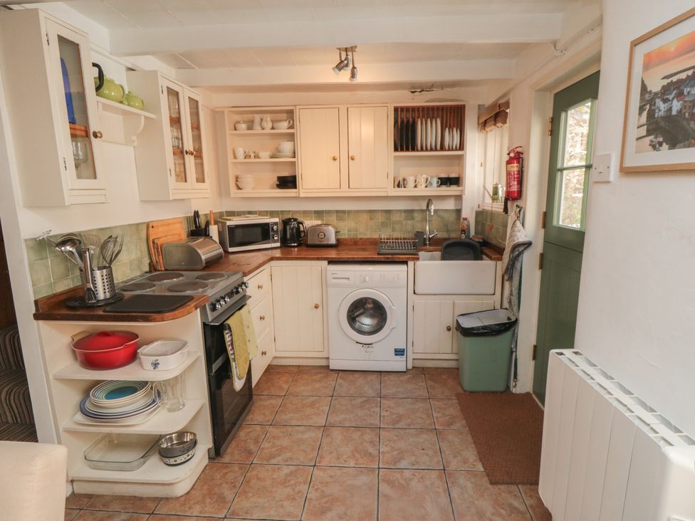 A kitchen with cabinets, stove, sink, and washing machine at Bulmers Cottage in Staithes