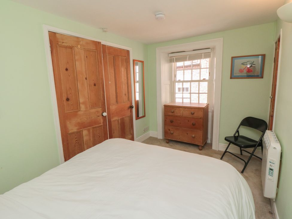 A bedroom with a bed and wardrobe at Bulmers Cottage in Staithes