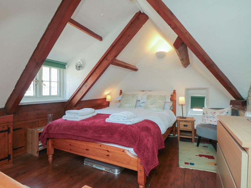 A bedroom with a large bed and a window at Bulmers Cottage in Staithes