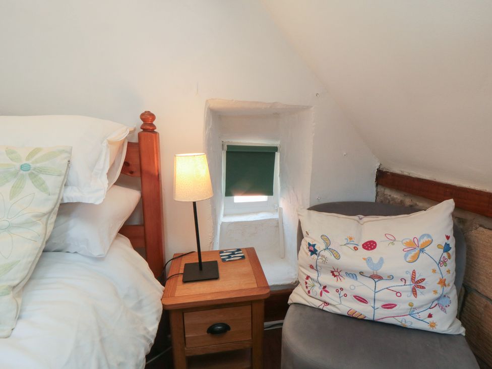 A bedroom with a bed and a nightstand at Bulmers Cottage in Staithes