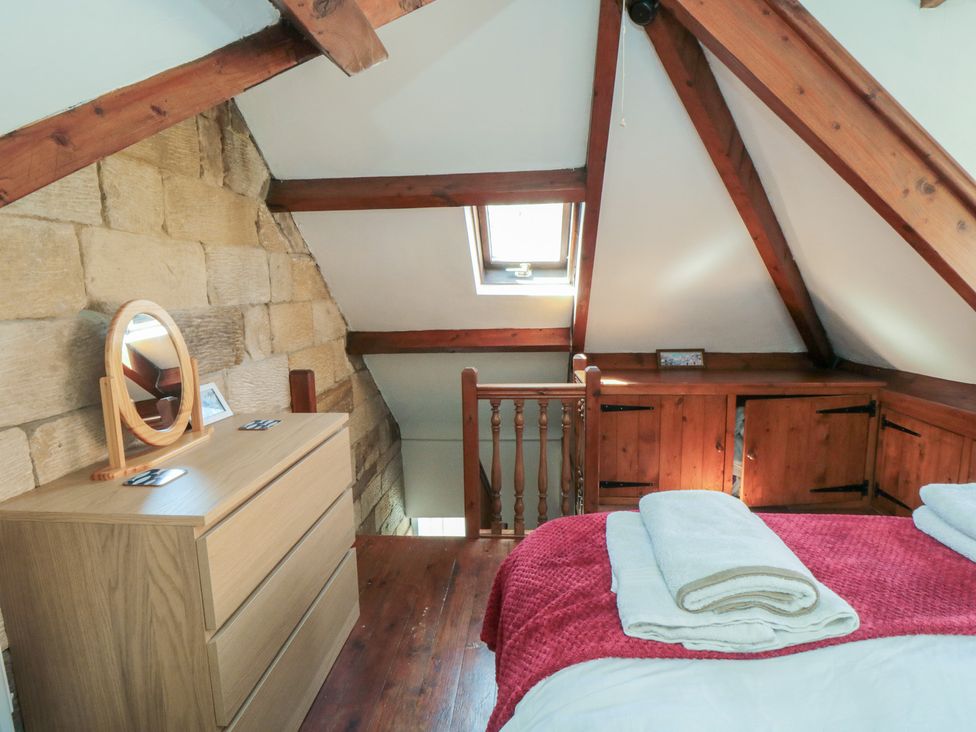 A bedroom with a bed and dressing table at Bulmers Cottage in Staithes