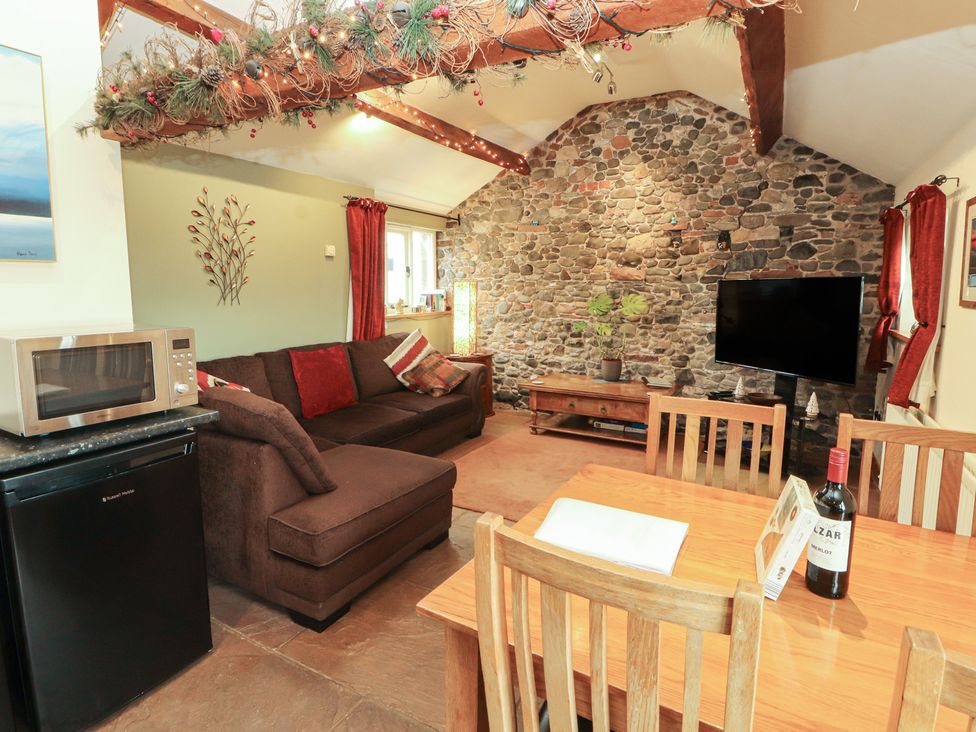 A living room with a sofa and dining table at Sonya's Cottage Anthorn, Solway Firth