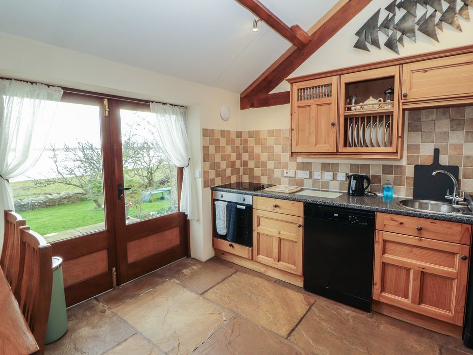 A kitchen with wooden cabinets and appliances at Sonya's Cottage in Anthorn, Solway Firth