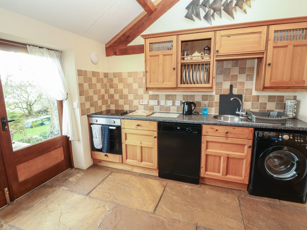 A kitchen with wooden cabinets and appliances at Sonya's Cottage in Anthorn, Solway Firth