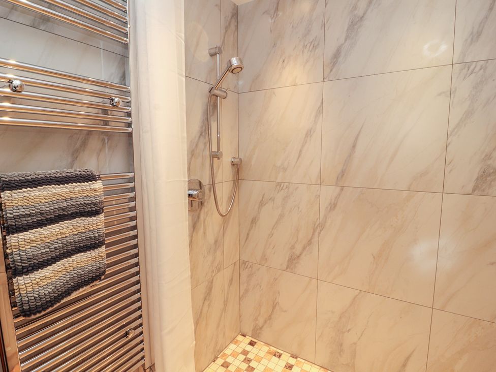 A shower with a towel radiator in Sonya's Cottage Anthorn, Solway Firth