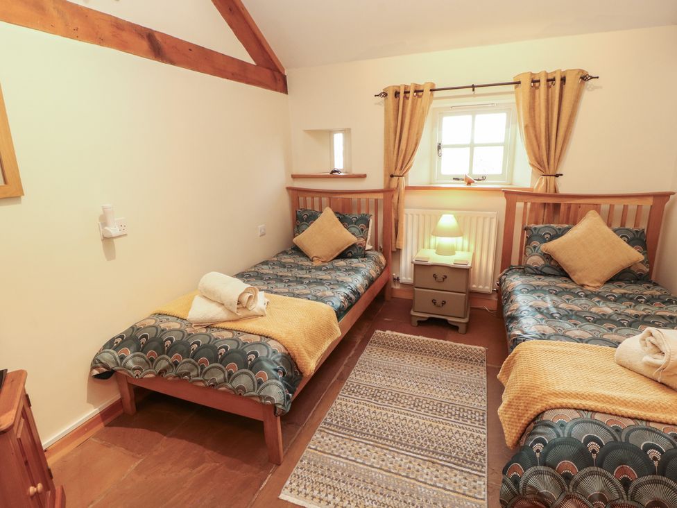 A bedroom with two beds and a bedside table at Sonya's Cottage Anthorn, Solway Firth