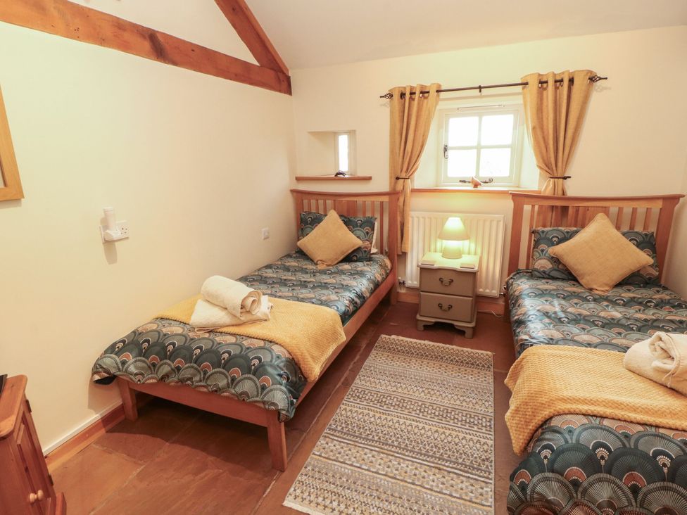A bedroom with two single beds and a nightstand at Sonya's Cottage in Anthorn, Solway Firth