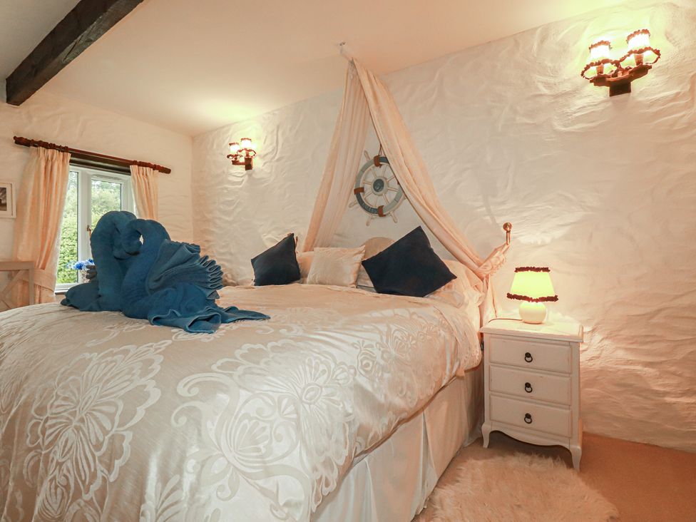 A bedroom with a bed and nightstand at Poldark Cottage East Taphouse