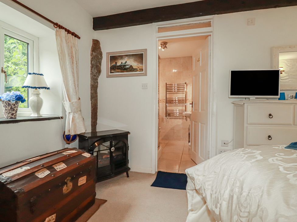 A bedroom with a window and a door leading to a bathroom at Poldark Cottage East Taphouse
