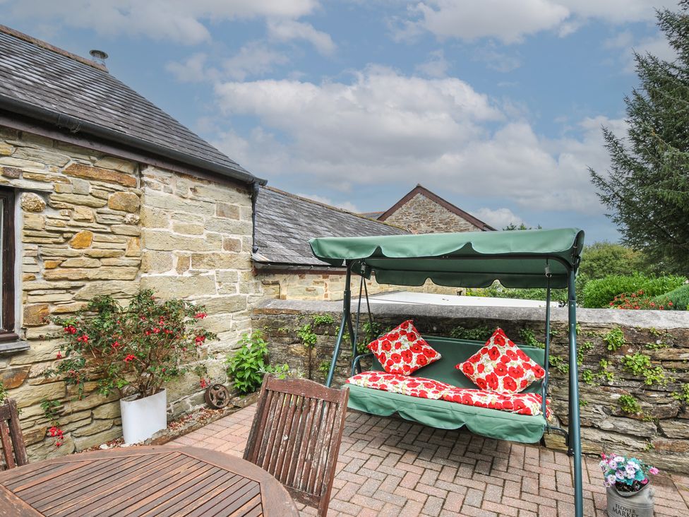 An outdoor area with a swing seat and a table at Poldark Cottage in East Taphouse
