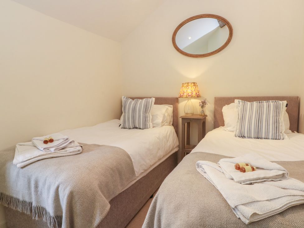 A bedroom with two beds and a bedside table with a lamp at The Hayloft in Northop near Chester