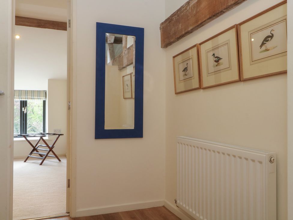 A hallway with a mirror and framed paintings at The Hayloft in Northop near Chester