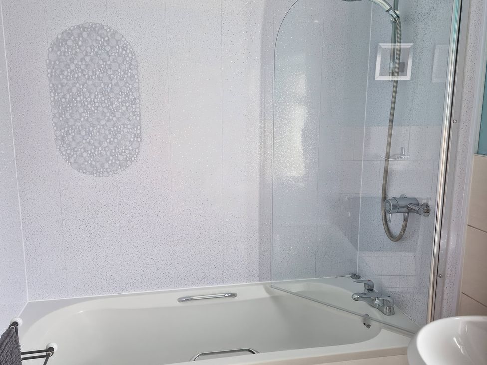 A bathroom with a bath tub and shower at Ty'r Enfys Bach - Upper Trearddur Bay