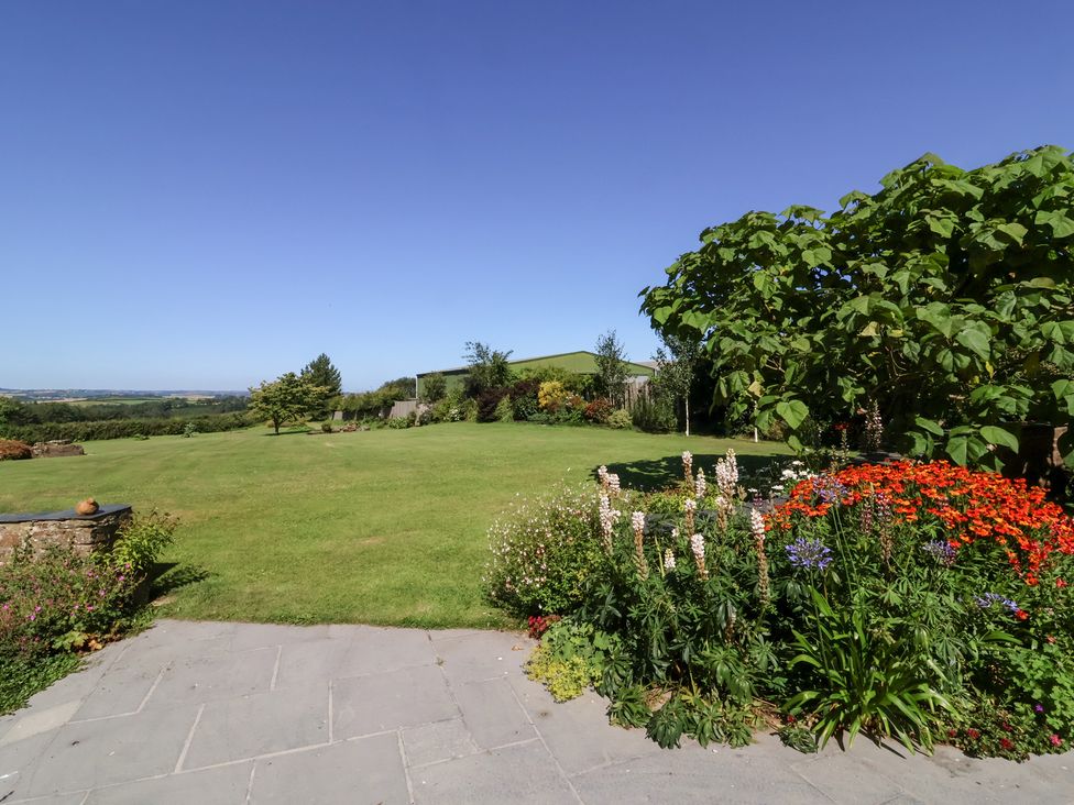 A garden with grass, trees, and flowers at Pound Cottage in Huntshaw near Great Torrington