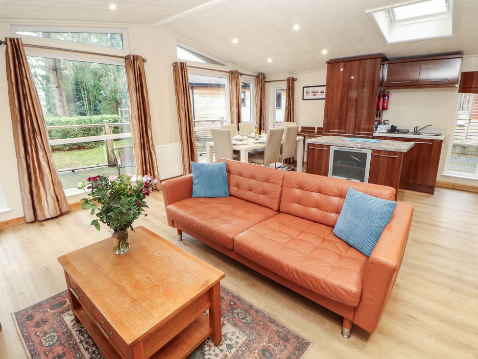 A living room with a sofa, coffee table, and dining area at Beech Hill Lodge (Beech Hill 9) at Fallbarrow Park