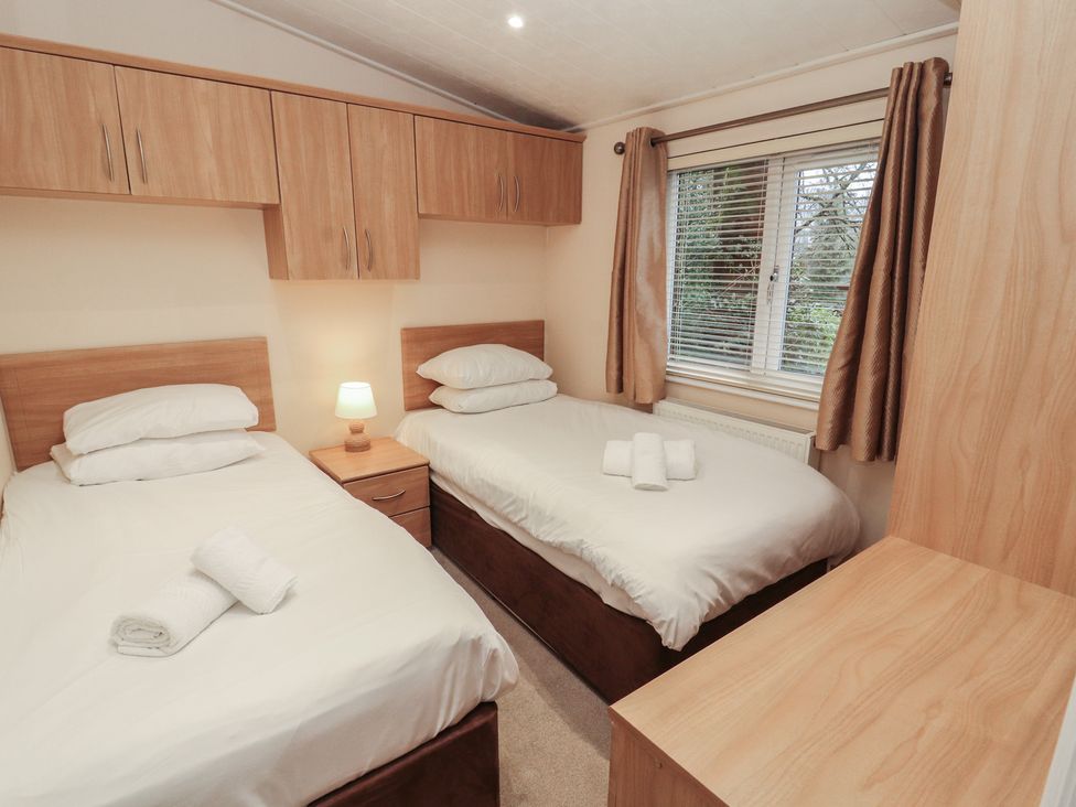 A bedroom with two single beds and a window at Beech Hill Lodge (Beech Hill 9) at Fallbarrow Park